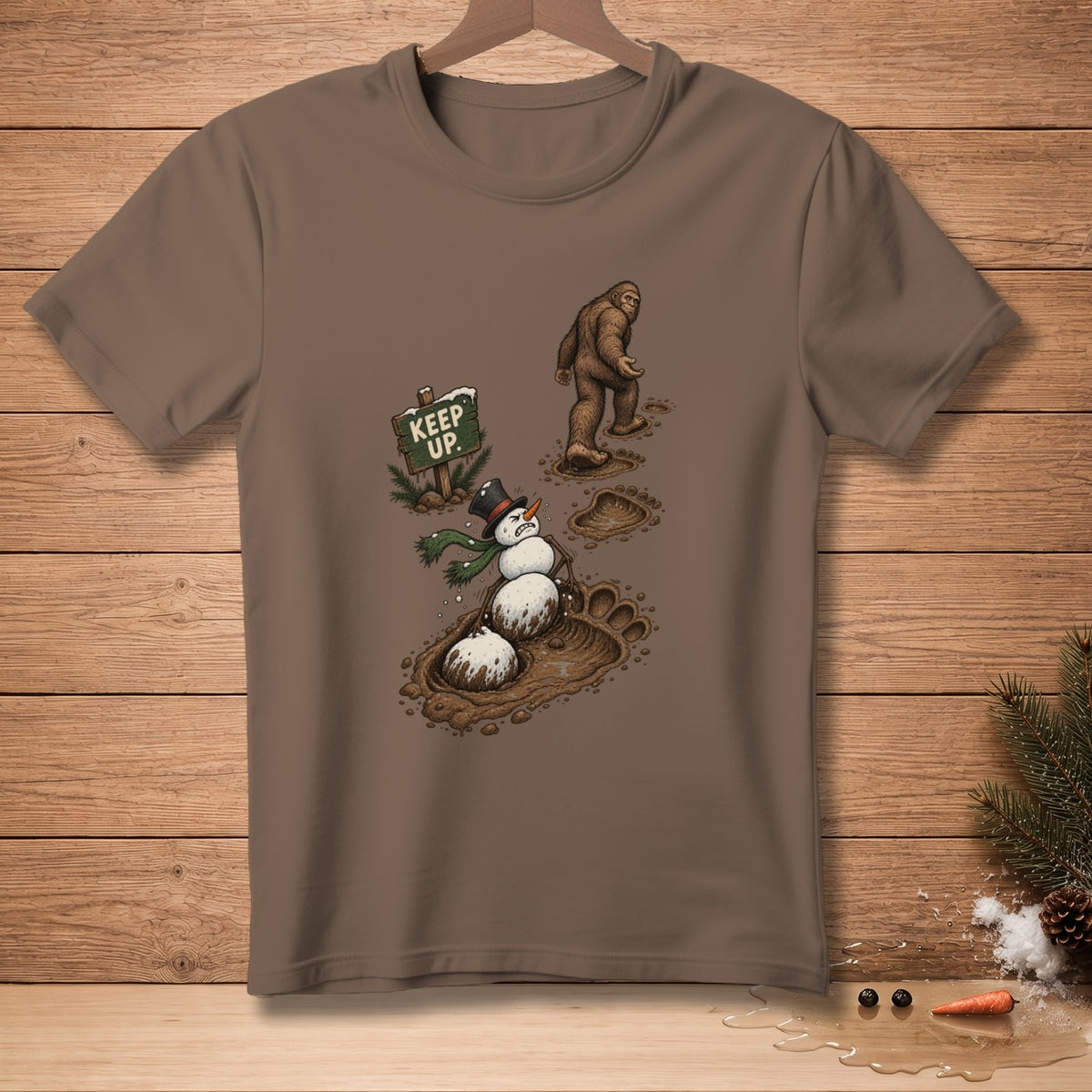 T-shirt graphic: Bigfoot walking past a melting snowman in mud.