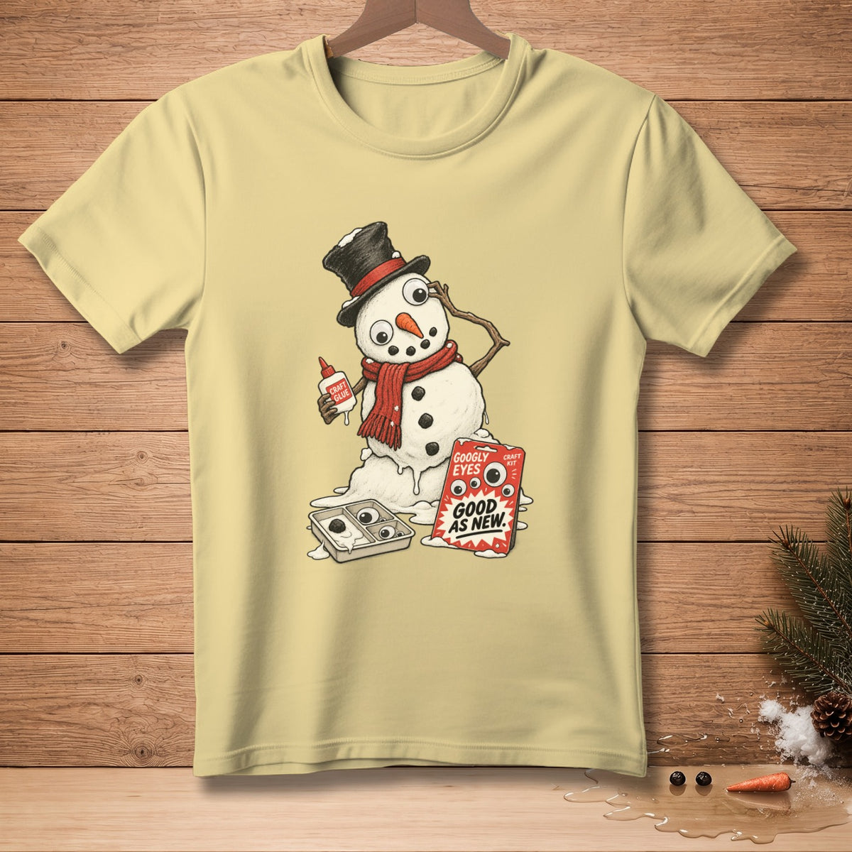 Snowman with googly eyes craft kit and glue on pale yellow t-shirt.