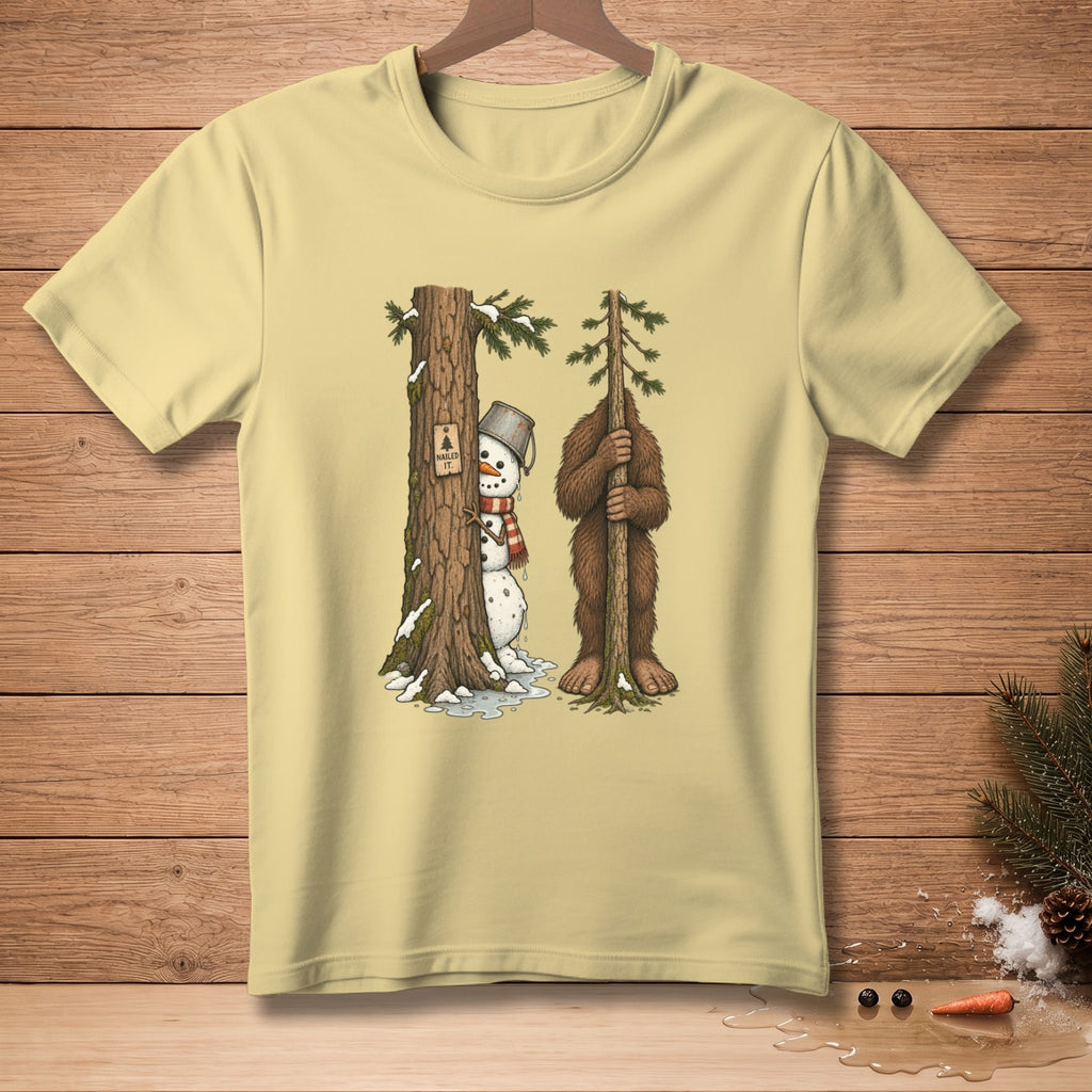 Snowman with bucket hat and scarf peeks from tree next to Bigfoot holding a tree.