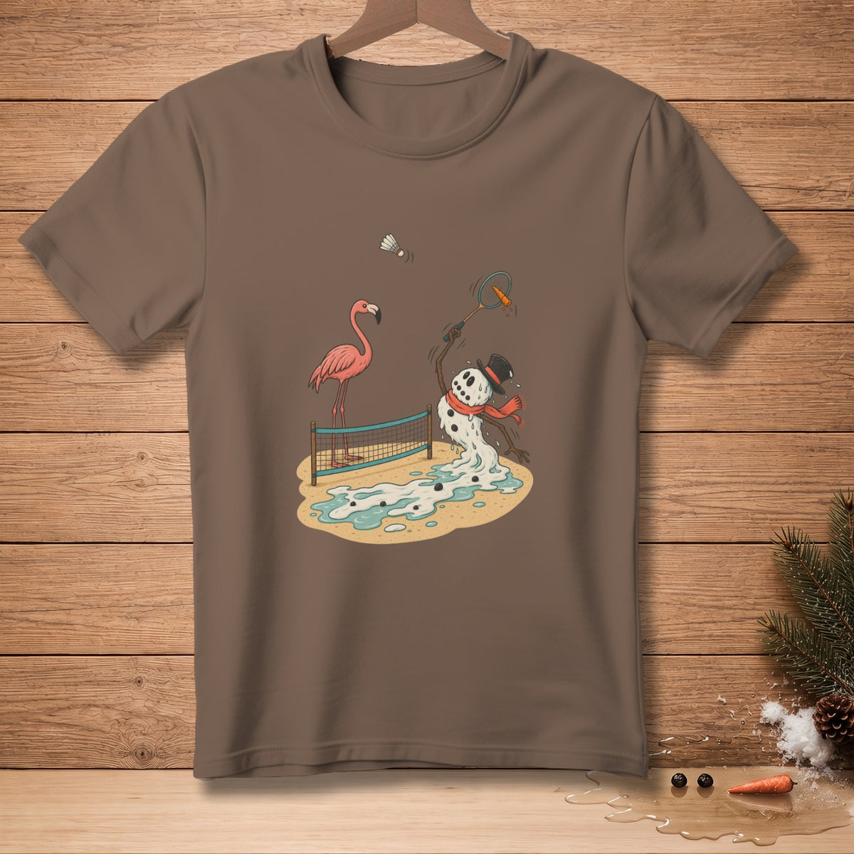 Brown t-shirt featuring a melting snowman playing badminton with a flamingo.