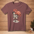 T-shirt with a flamingo offering a drink to a melting snowman at a table.