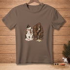 Brown t-shirt with a snowman and Bigfoot melting ice cream on a bench.