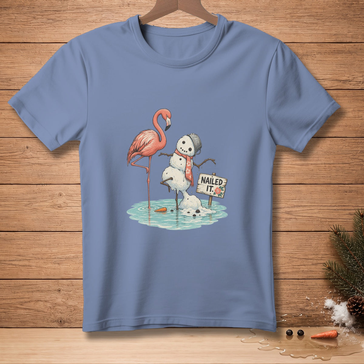 Melting snowman with flamingo and "Nailed It." sign graphic on light blue t-shirt.