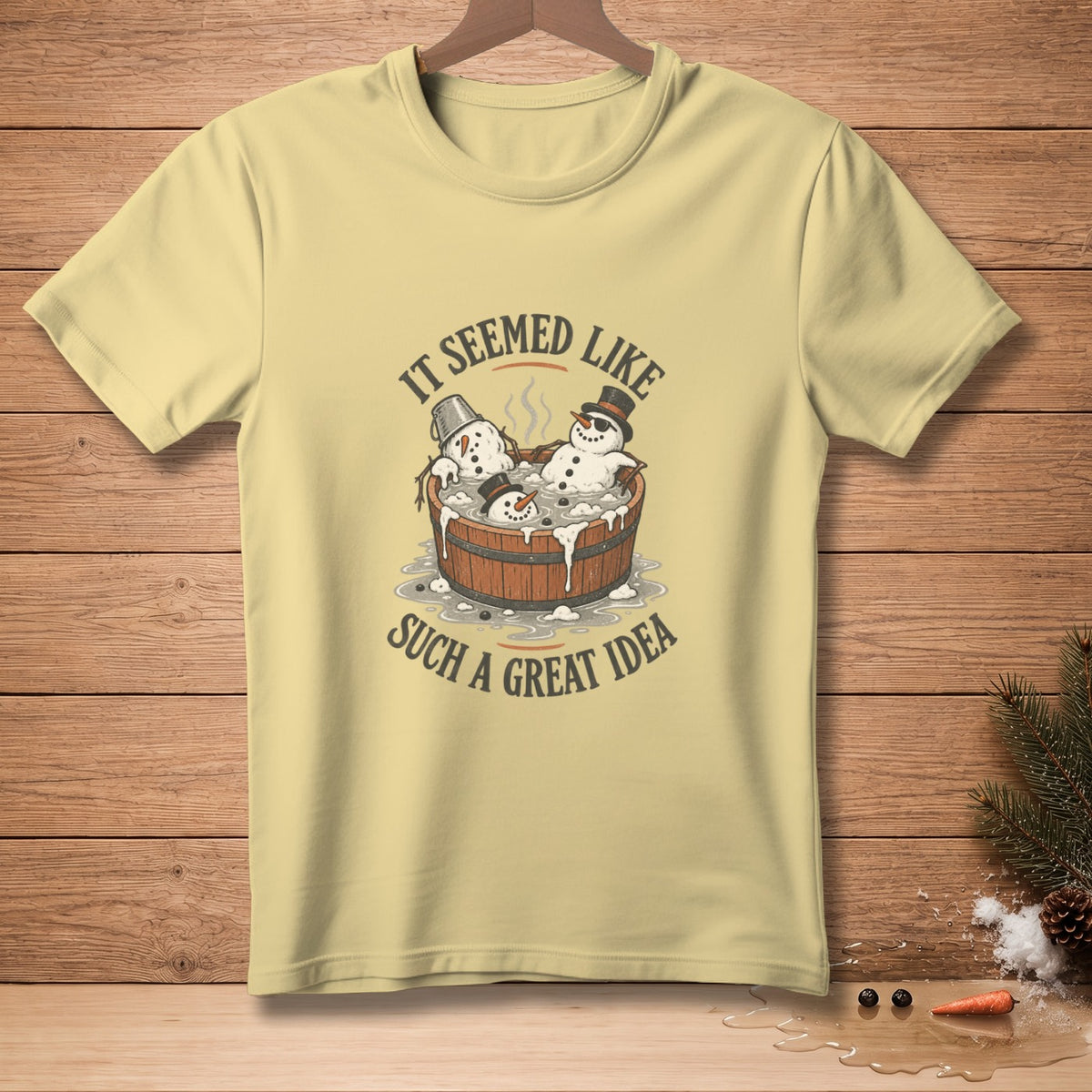 Light yellow t-shirt with snowmen in a tub graphic and text "It Seemed Like Such a Great Idea."