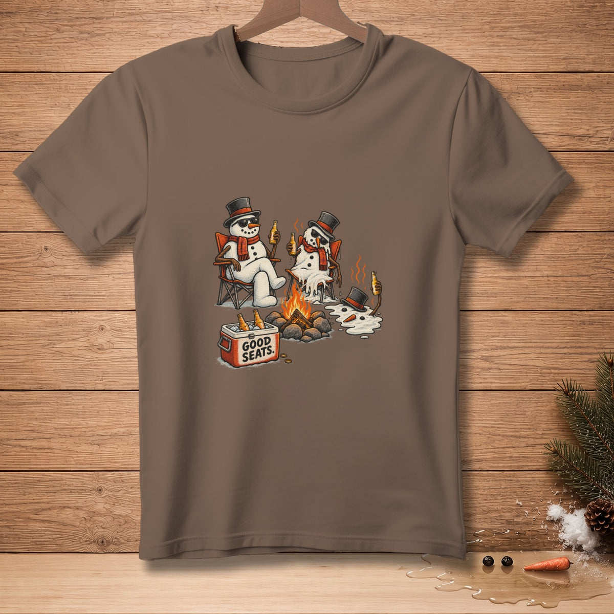 Melting snowmen wearing hats and scarves sit by a campfire, with a cooler labeled "GOOD SEATS."