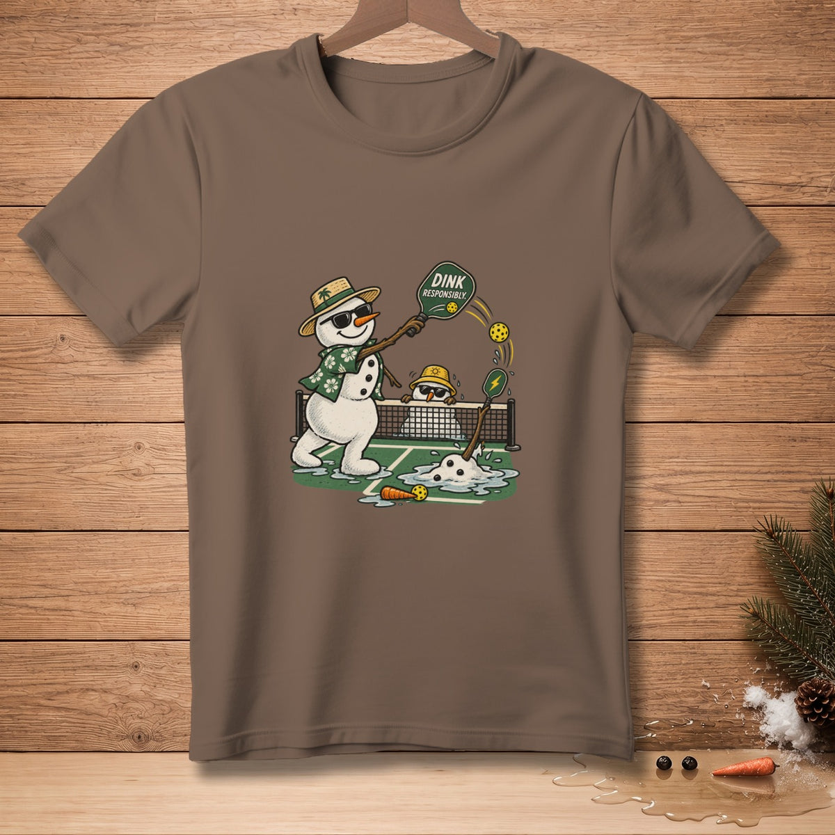 Two snowmen playing pickleball on a court with a net, one holding a paddle that says "DINK RESPONSIBLY".