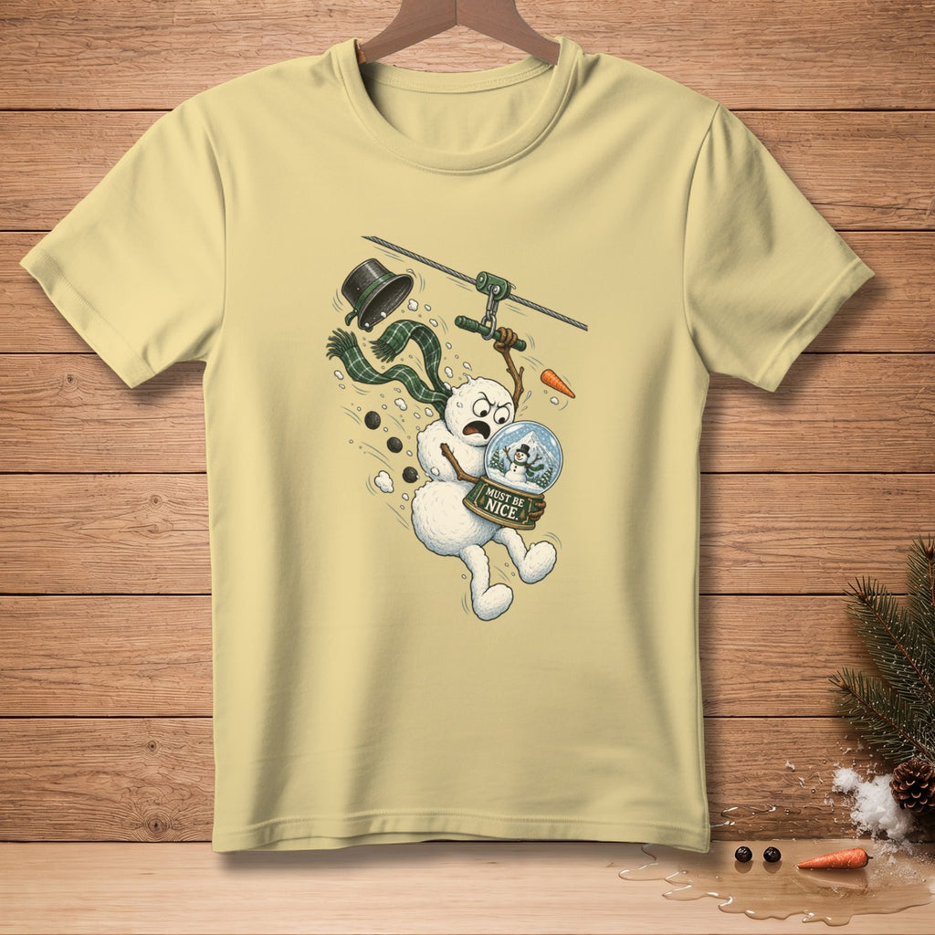 Yellow t-shirt with a snowman on a zipline holding a snow globe, text reads "Must Be Nice."