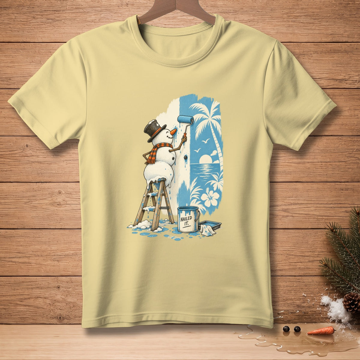Snowman painting a tropical beach scene on a light yellow t-shirt.