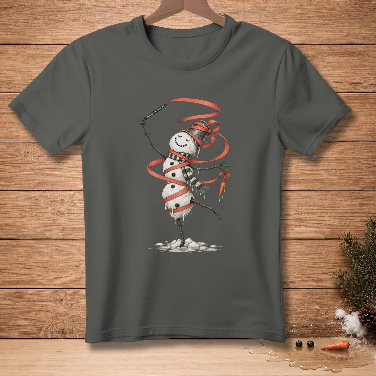 Snowman with melting parts, wrapped in red ribbon, holding carrot, on dark gray t-shirt.