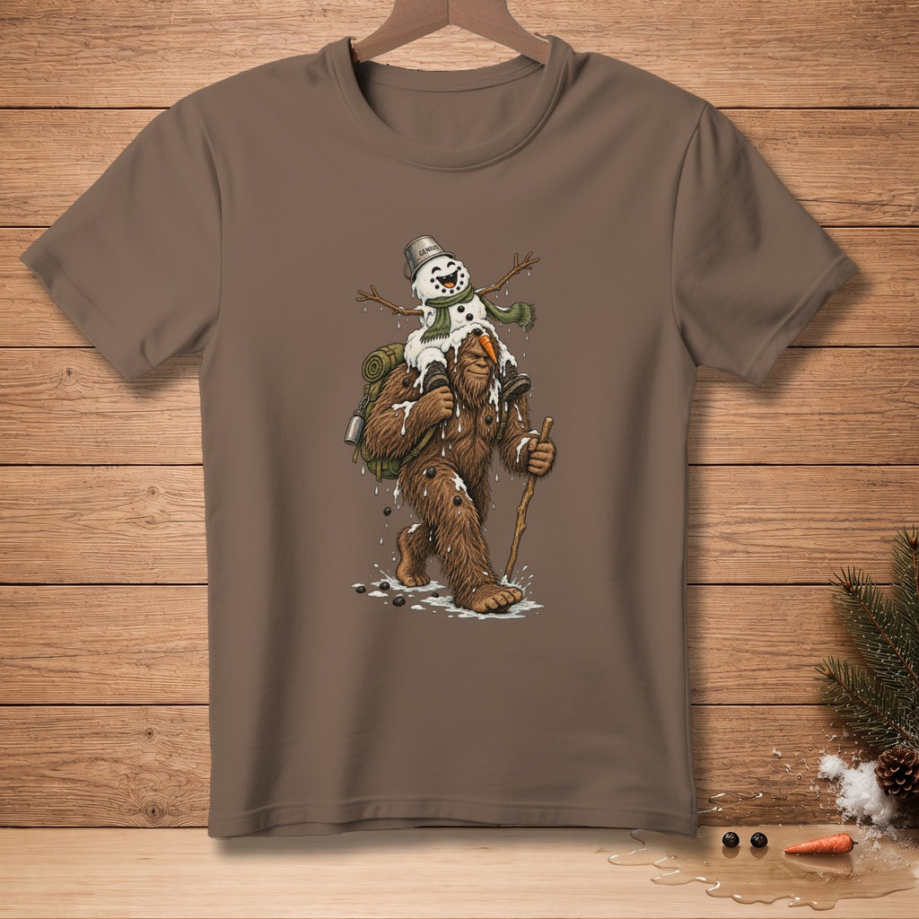 Brown t-shirt featuring Bigfoot carrying a melting snowman with "Genius" on its bucket.