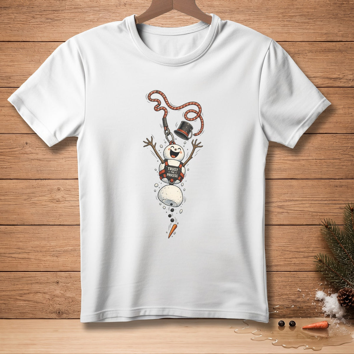 White t-shirt with a falling snowman graphic reading "Trust the Process."