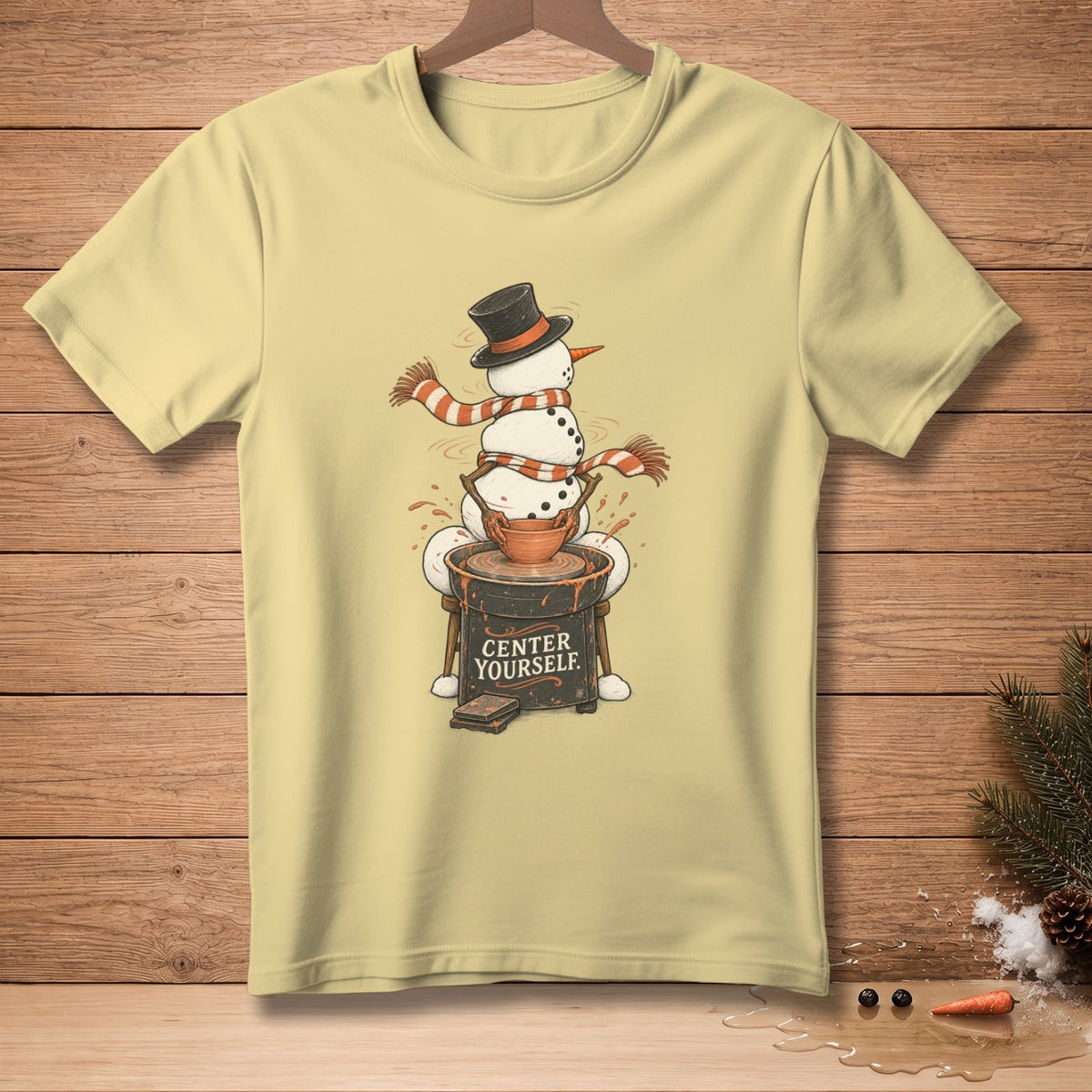 Pale yellow t-shirt with a snowman making pottery, text "CENTER YOURSELF."
