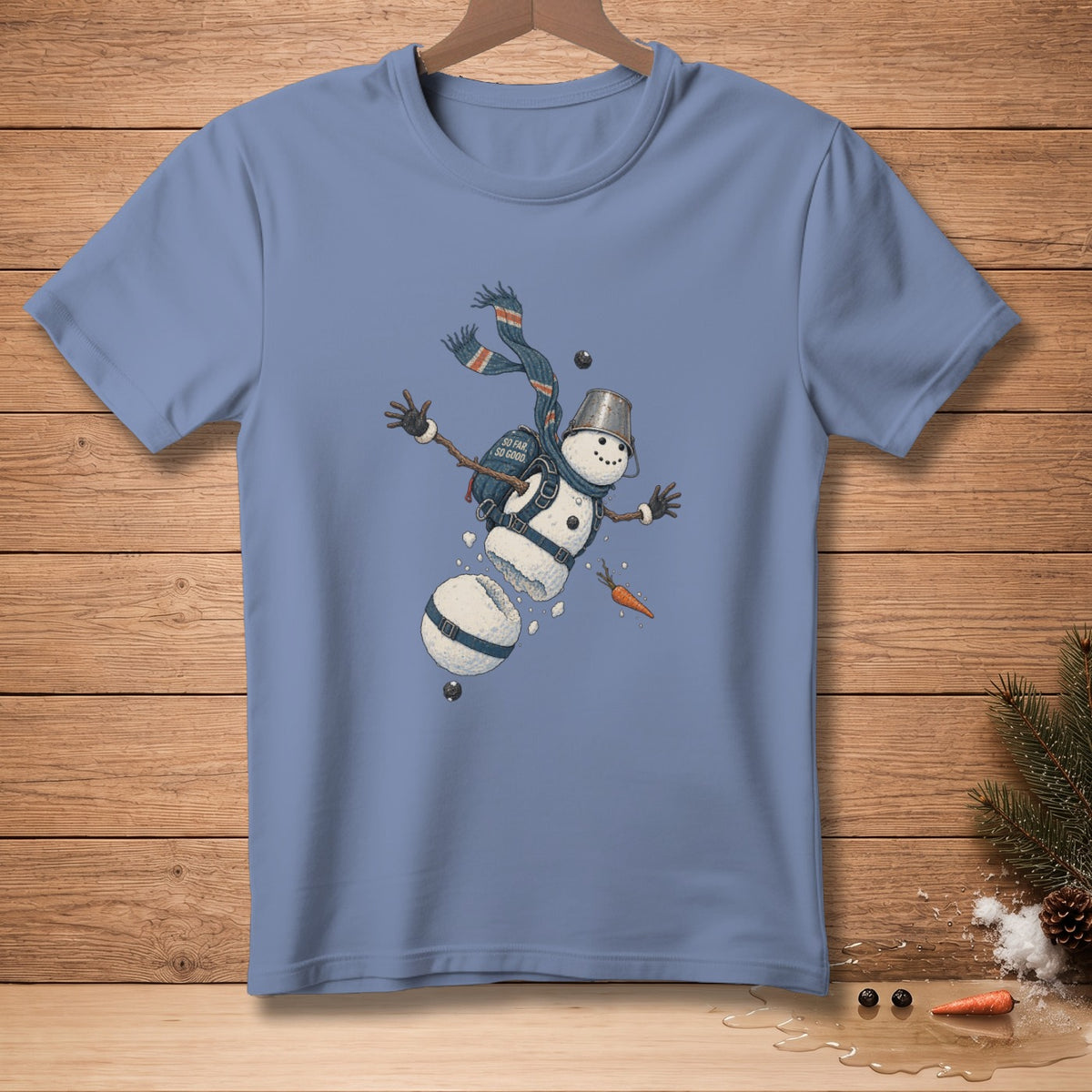 Blue t-shirt with falling snowman graphic featuring a bucket hat and scarf.