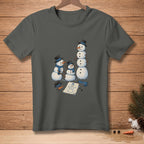 T-shirt with a humorous graphic of three snowmen being built, with a drawing of a snowman on paper.