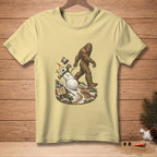 Bigfoot walks past a fallen snowman with a sign reading "Nailed the walk."