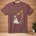 Giraffe feeding a melting snowman a carrot on a maroon t-shirt.