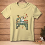 T-shirt graphic of snowman and pelican fishing on a pier with "NATURAL FISHERMAN" text.