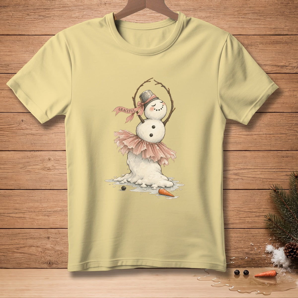 Light yellow t-shirt with a graceful dancing snowman wearing a pink tutu and hat.