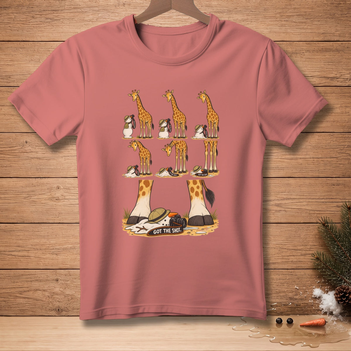 Giraffes and snowmen on a pink t-shirt, one snowman has a camera and reads "GOT THE SHOT."