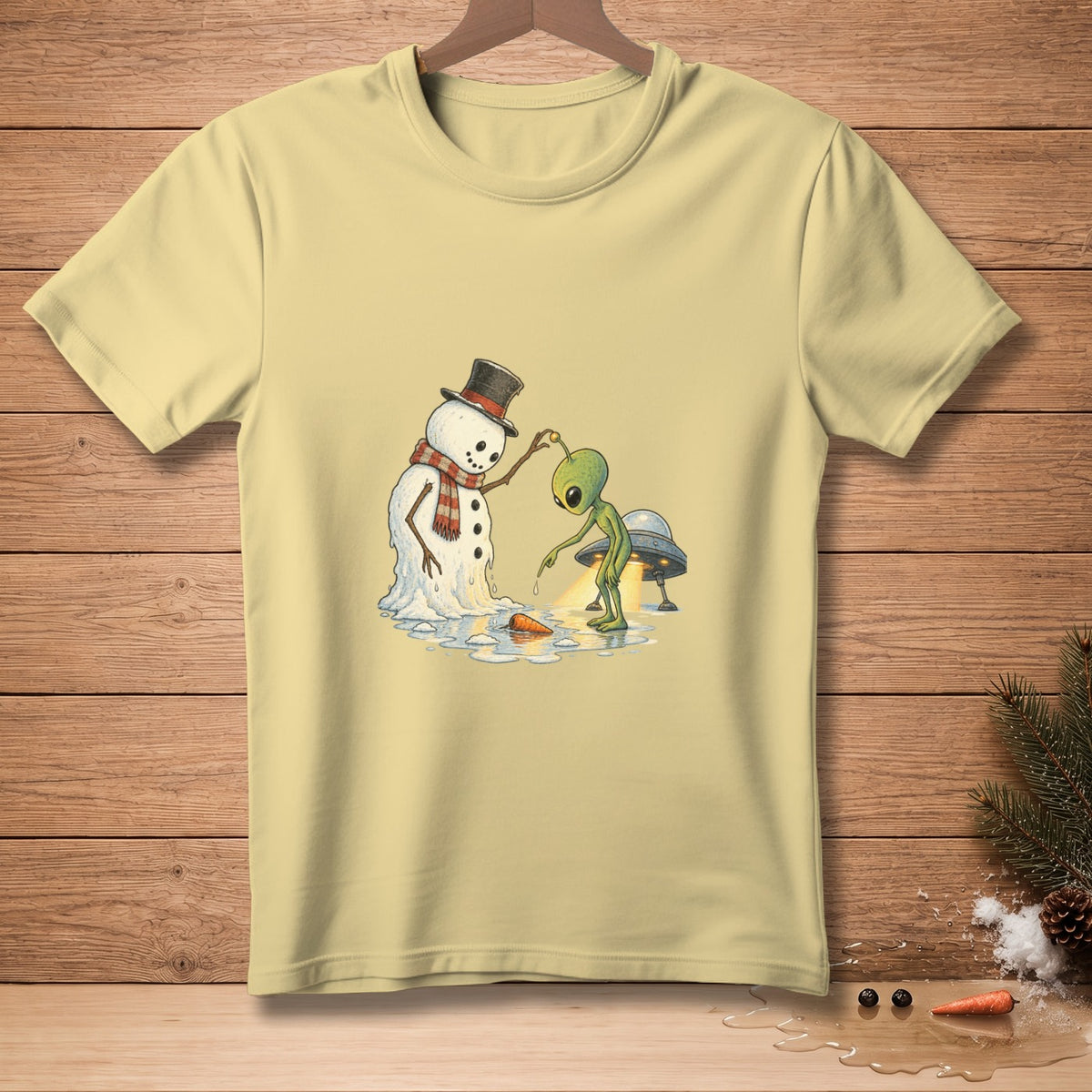 Alien interacting with a melting snowman and UFO on a light yellow t-shirt.