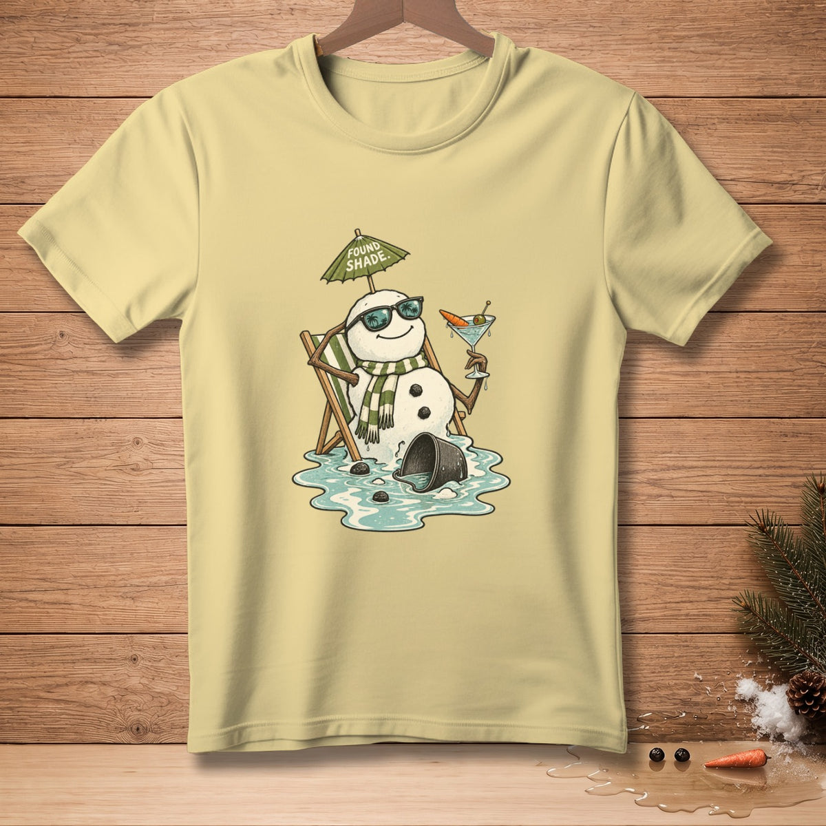 Light yellow t-shirt with a melting snowman in sunglasses holding a drink under an umbrella.