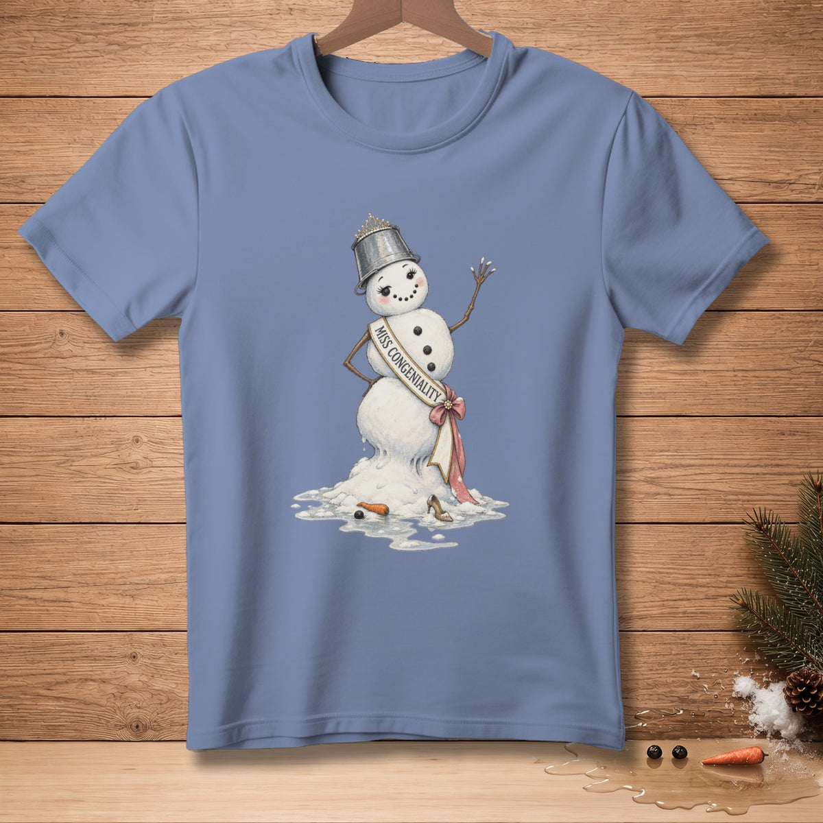 Melting snowman with tiara and sash labeled "Miss Congeniality" on blue t-shirt.