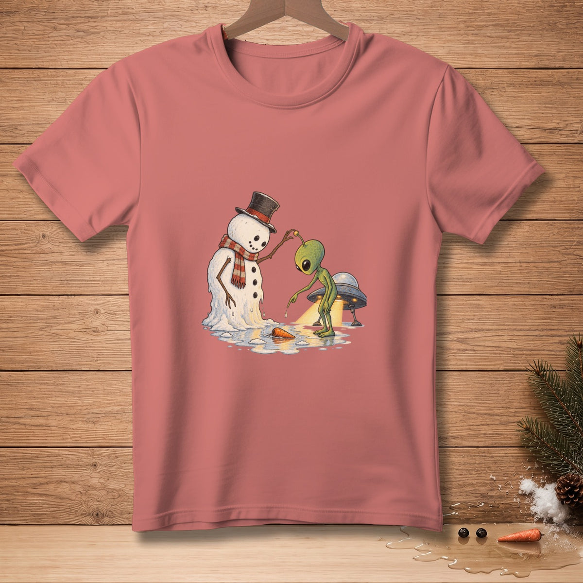 Alien interacting with melting snowman and UFO on pink t-shirt.