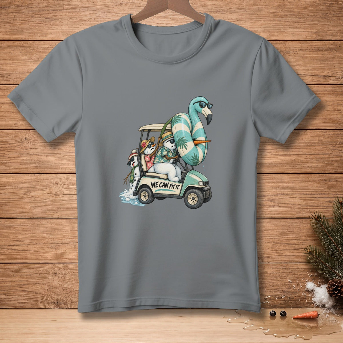 T-shirt with cartoon snowmen driving a golf cart with a flamingo float, text reads "WE CAN FIT IT."