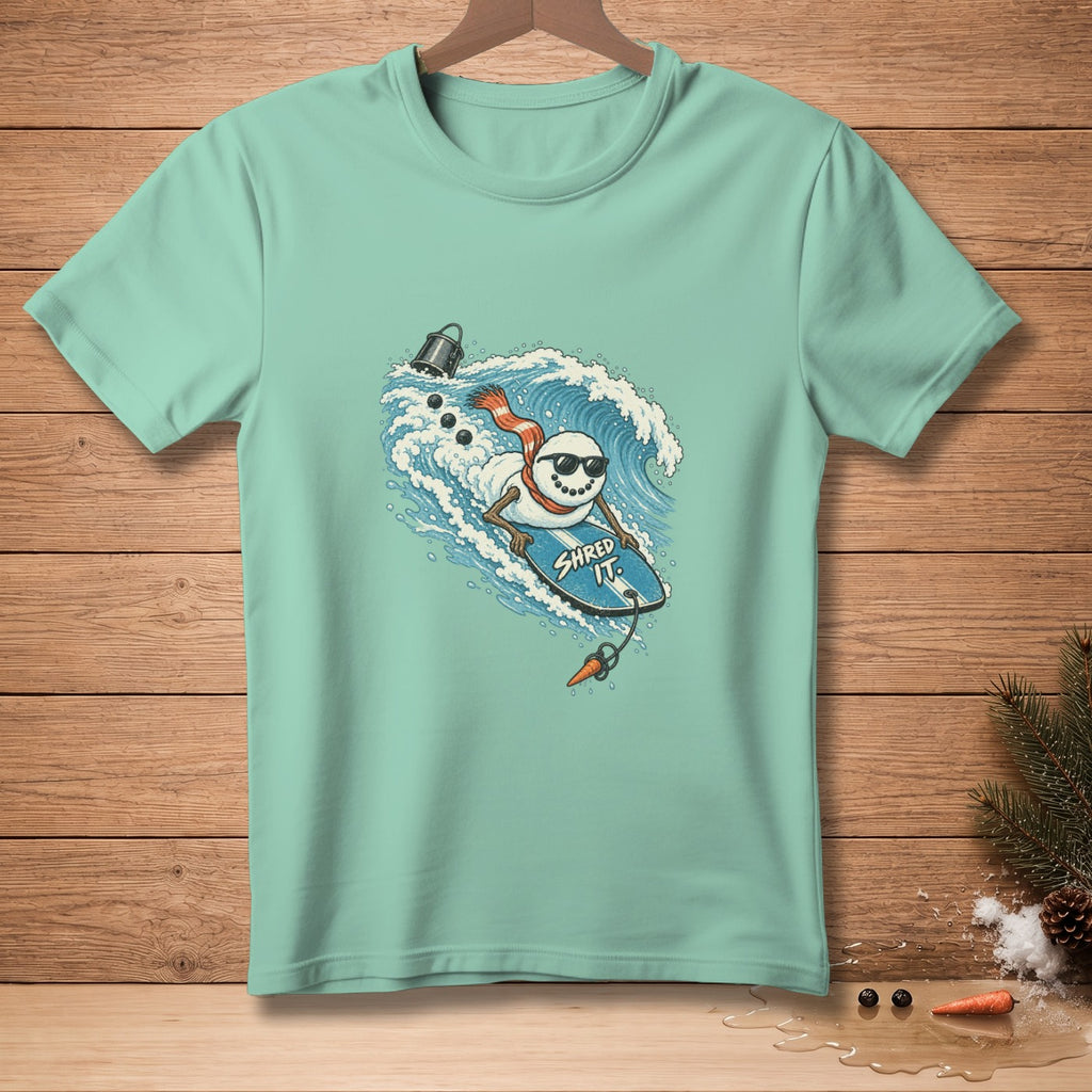 Snowman surfing a wave on a surfboard with "SHRED IT." text.