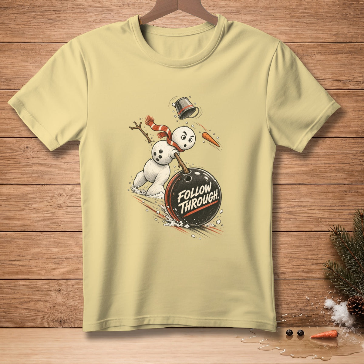 Snowman bowling with text "FOLLOW THROUGH" on a light yellow t-shirt.