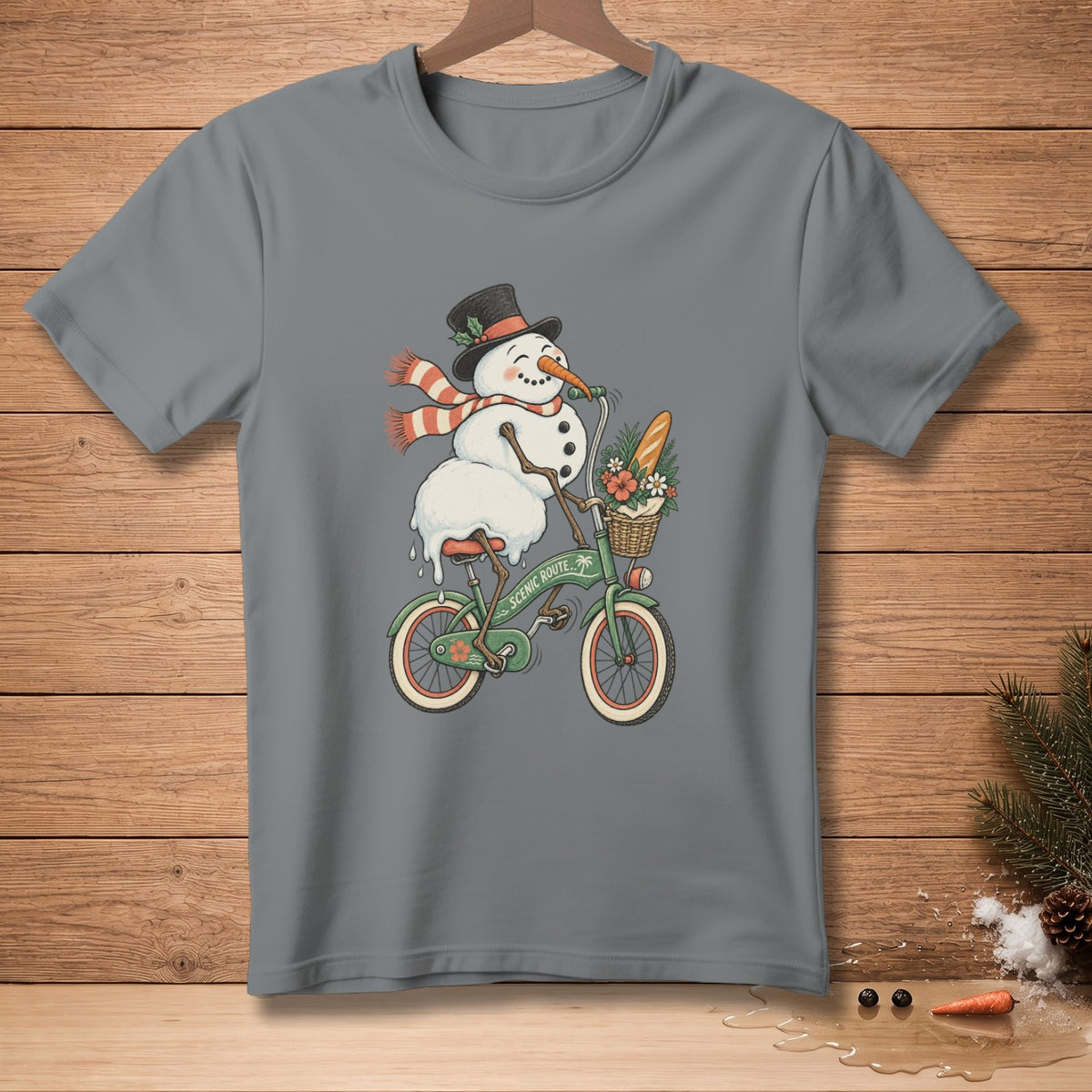 Grey t-shirt with a cartoon snowman wearing a top hat and scarf riding a bicycle.