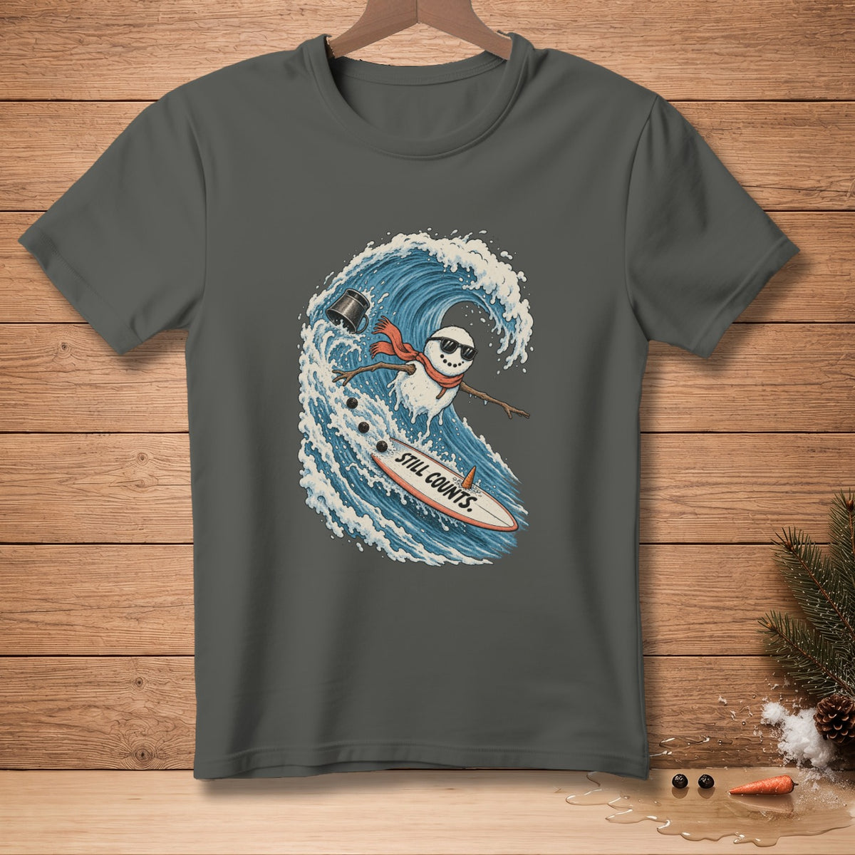 Dark gray t-shirt with a surfing snowman graphic saying "Still Counts."