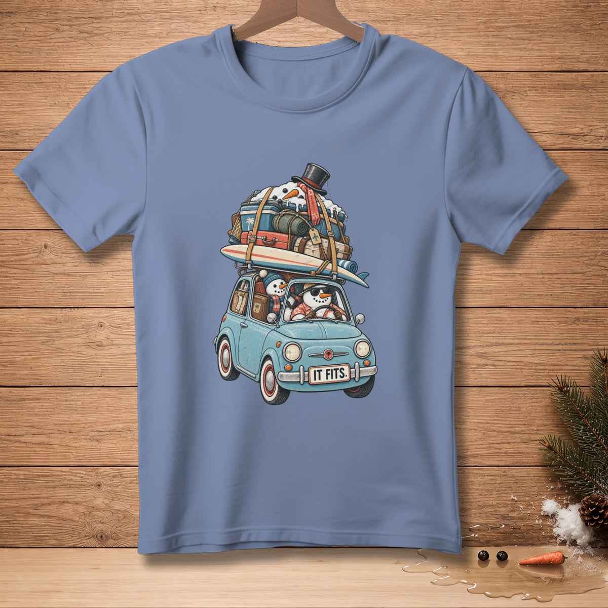 Blue t-shirt featuring snowmen in a car packed with luggage and a surfboard.