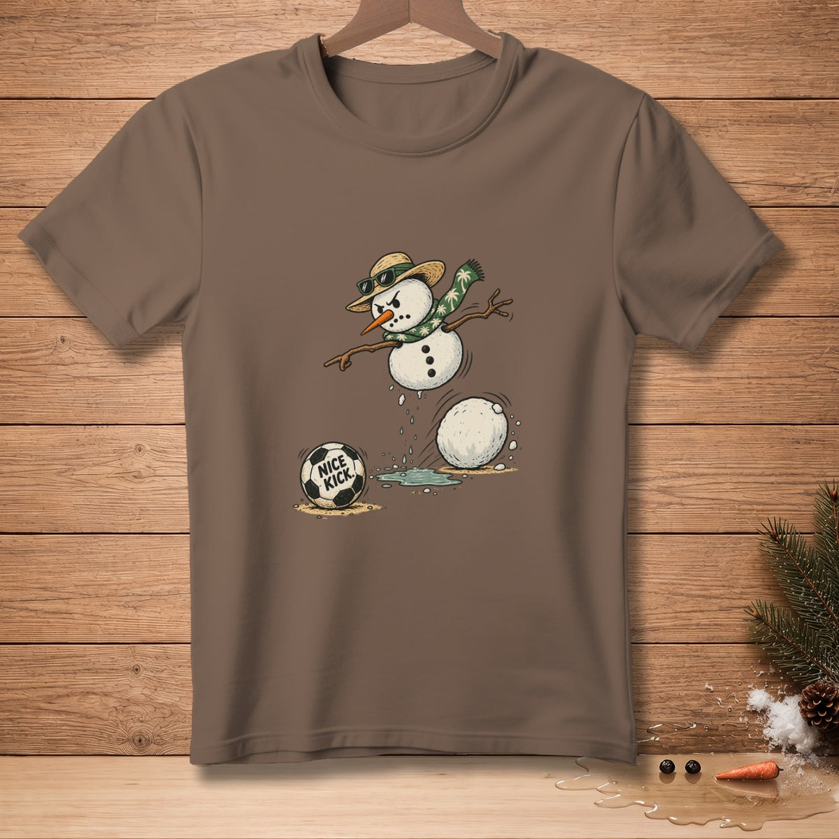 Brown t-shirt with a cartoon snowman kicking a soccer ball that says "NICE KICK".