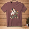 Snowman wearing hat and scarf rides bicycle with flowers and bread in basket.