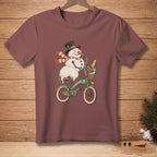 Snowman wearing hat and scarf rides bicycle with flowers and bread in basket.