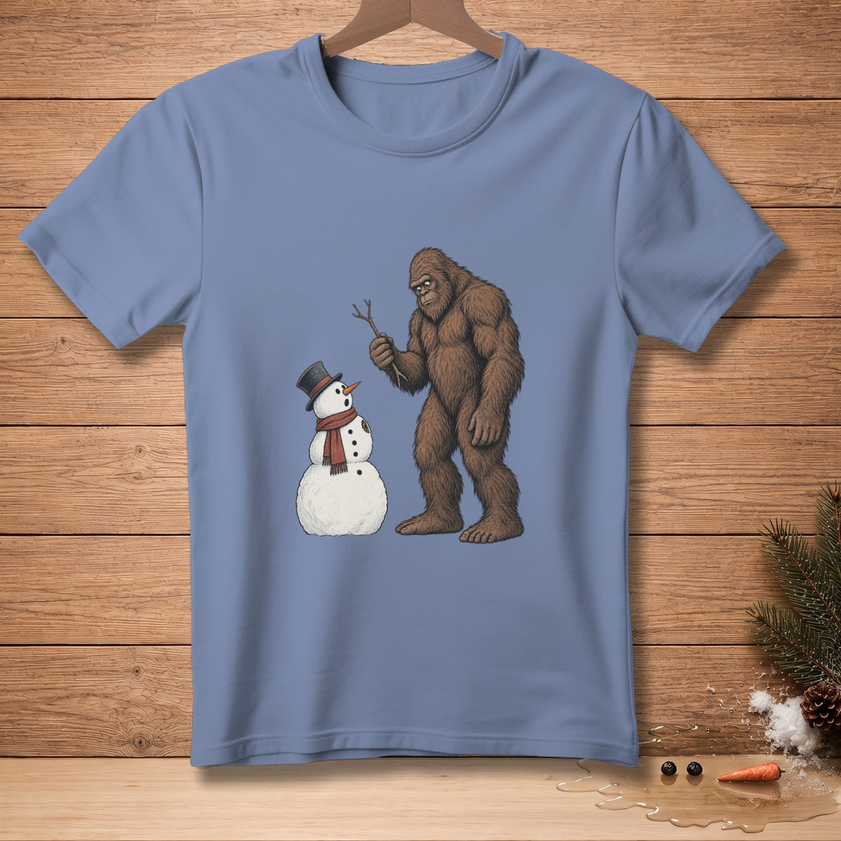 Bigfoot holding a stick to a snowman on a blue t-shirt.