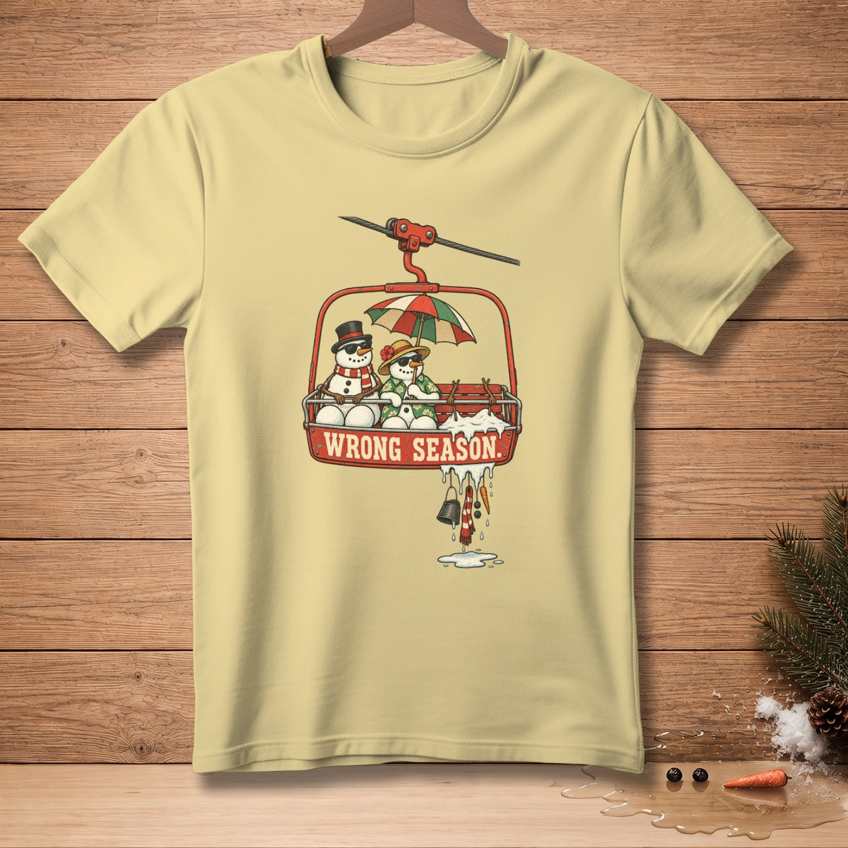 Light yellow t-shirt with snowmen on a ski lift with "WRONG SEASON" text.