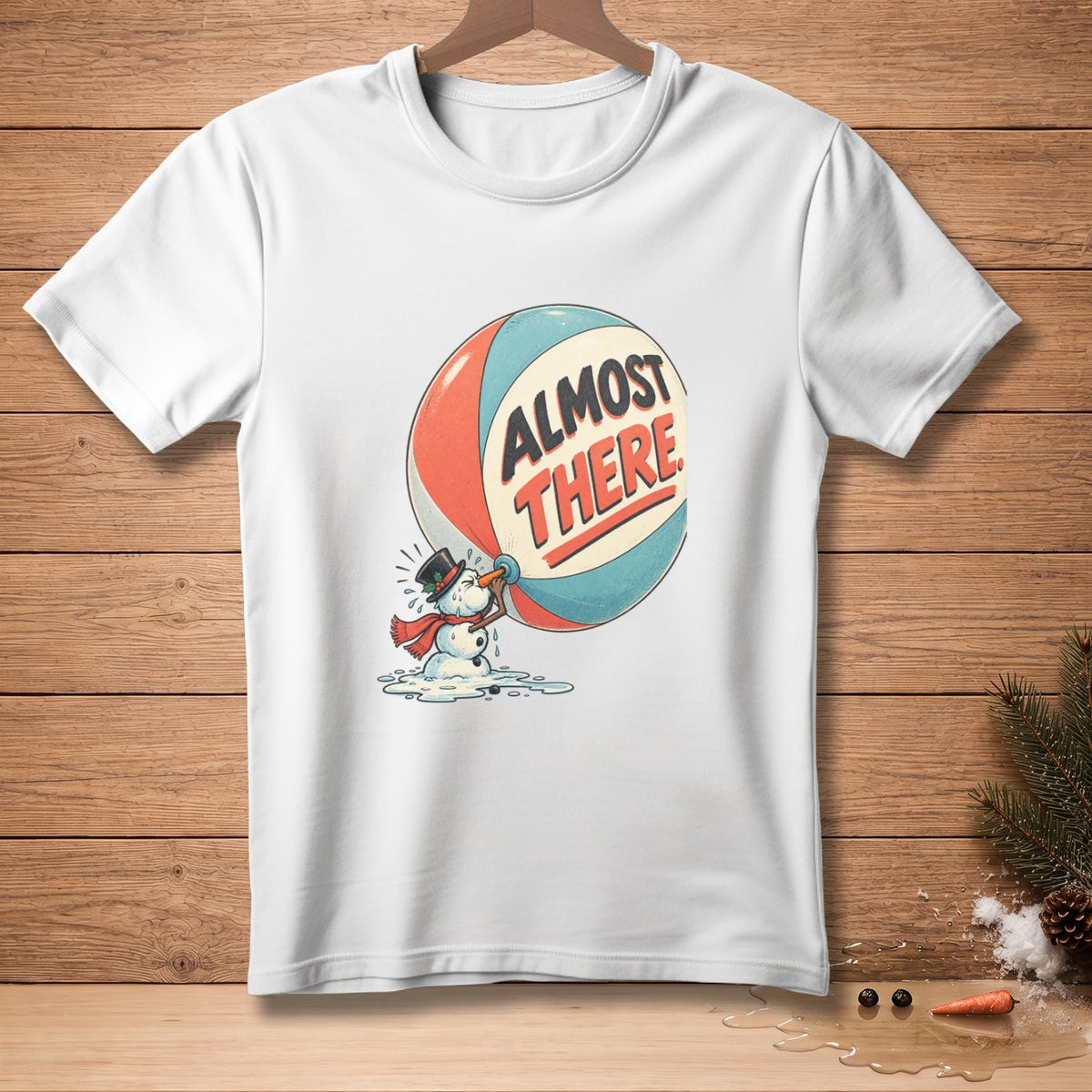 White t-shirt with melting snowman drinking from a ball that says "ALMOST THERE".