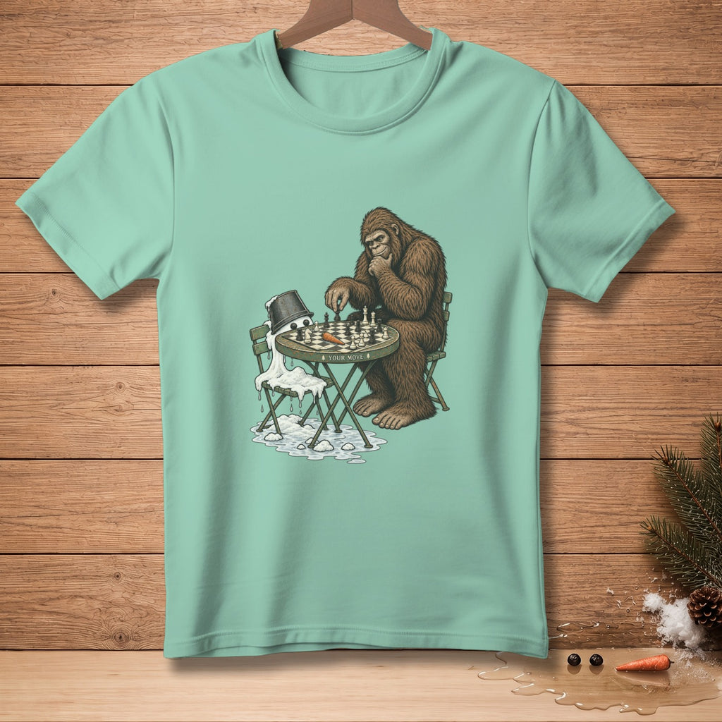 Bigfoot plays chess against a melting snowman on a t-shirt.