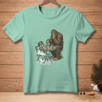 Bigfoot plays chess against a melting snowman on a t-shirt.