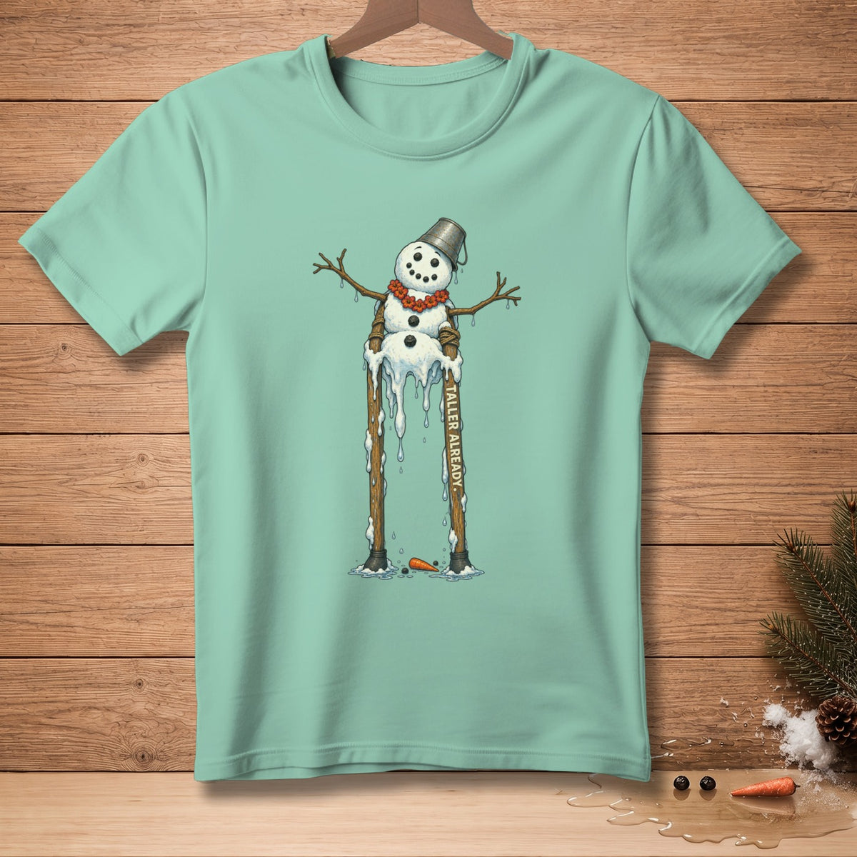 Mint t-shirt featuring a melting snowman on stilts with "TALLER ALREADY" text.