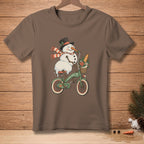 Snowman in a top hat and scarf rides a bicycle with a basket of flowers and bread.