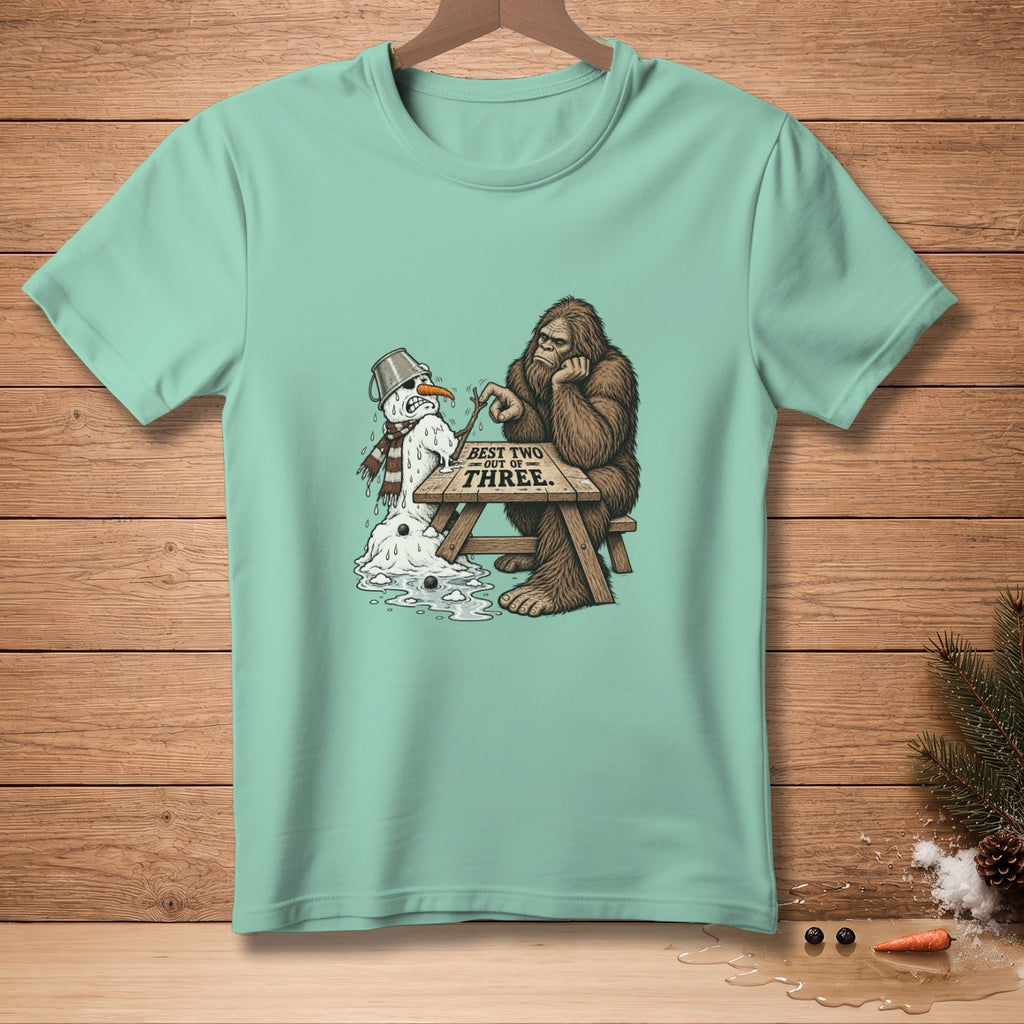 Bigfoot playing rock paper scissors with a melting snowman, text "BEST TWO OUT OF THREE".