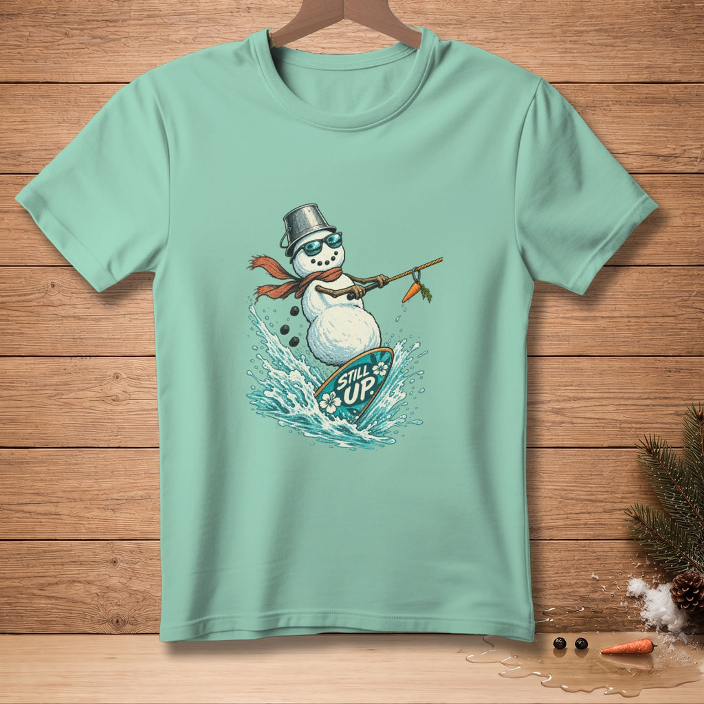 Snowman surfing on a surfboard with "Still Up" text, wearing a bucket hat and scarf.