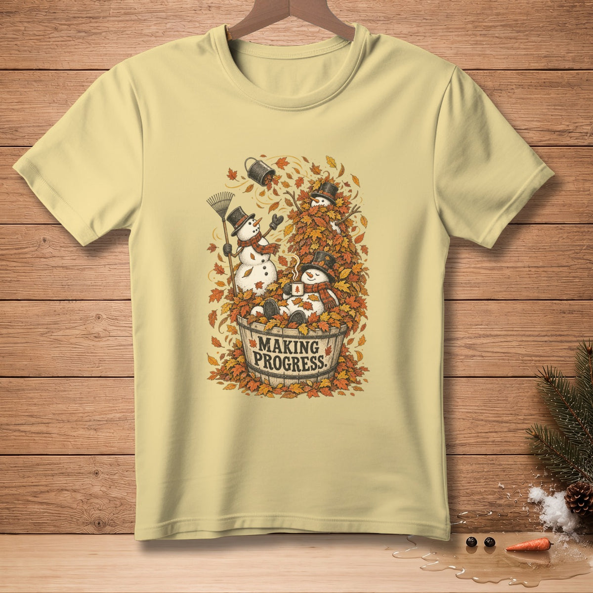 Yellow t-shirt with snowmen playing in autumn leaves and text "MAKING PROGRESS."