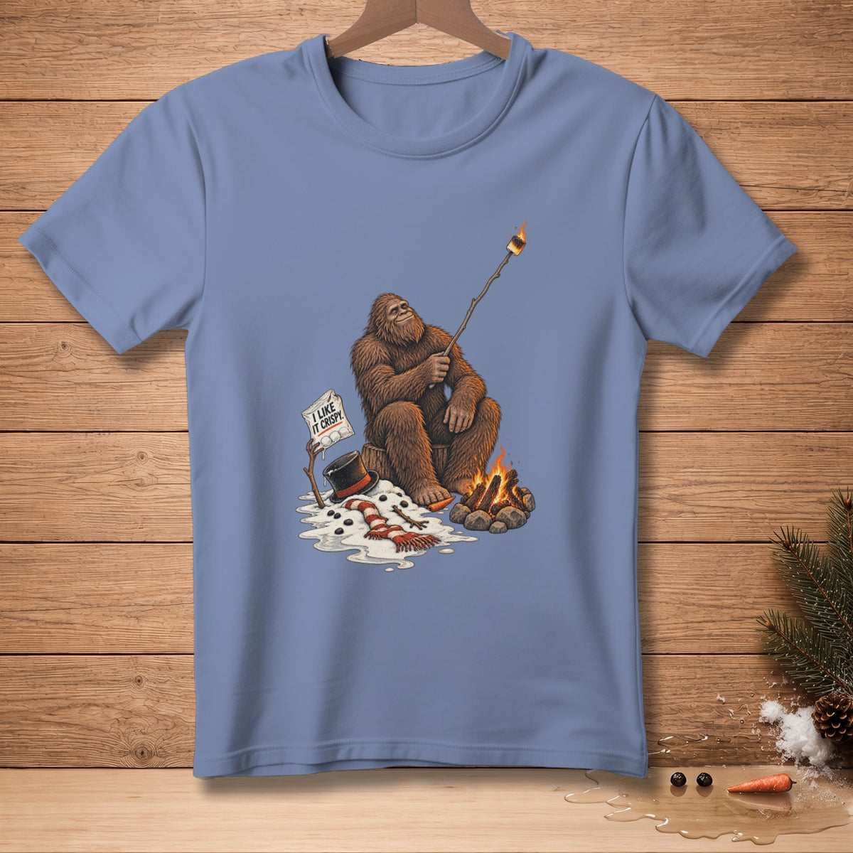 Bigfoot roasts a marshmallow over a campfire with a sign that says "I like it crispy."
