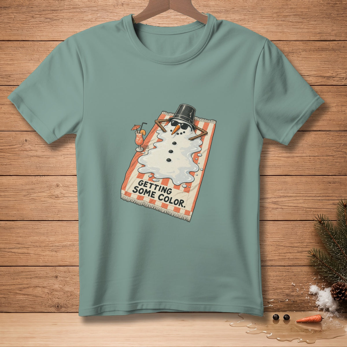 T-shirt graphic of a melting snowman on a beach towel with a drink, text says "GETTING SOME COLOR."