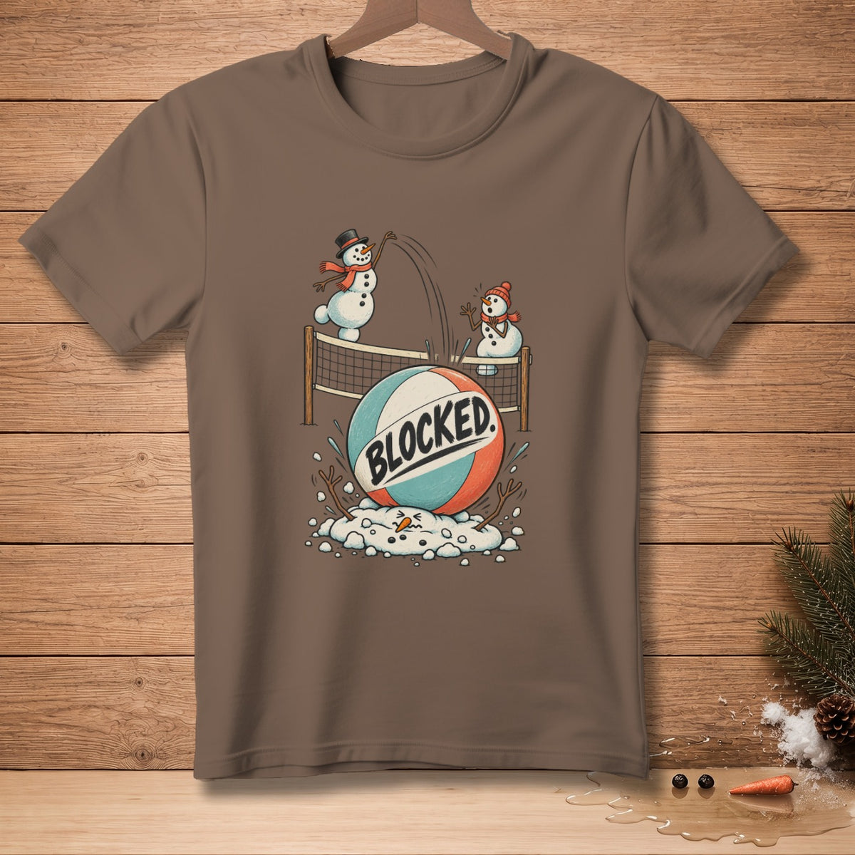 Snowmen playing volleyball with a ball labeled "BLOCKED" on a brown t-shirt.