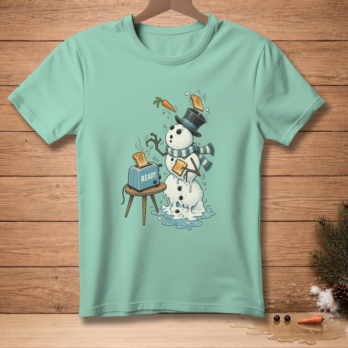 Melting snowman with a toaster, carrot, and toast on a mint green t-shirt.